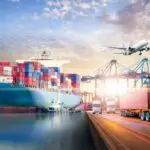 Customs officer inspecting industrial goods shipment at port with container yard and export documents, representing customs clearance process.